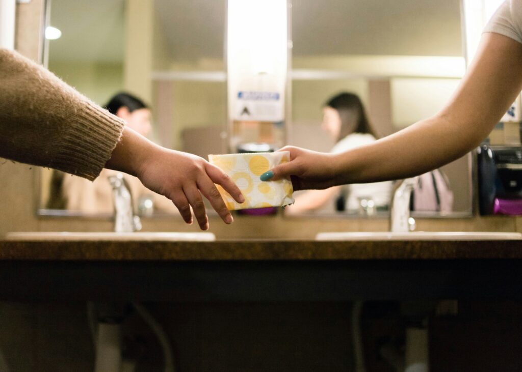 women holding a wrapped sanitary napkin
